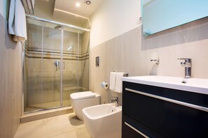 A modern bathroom with a glass shower enclosure, a white toilet, a bidet, and a vanity with a mirror. - Residence Le Axidie Sure Hotel Collection by BW (Vico Equense)