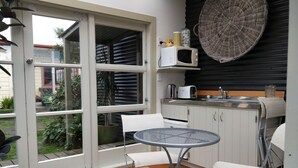 Una cocina compacta con microondas, tostadora y lavamanos. Hay un pequeño comedor con una mesa redonda y dos sillas.