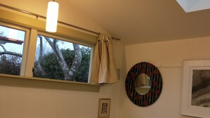 Un dormitorio con tragaluces, una cama con almohadas a rayas, una mesita de noche y un espejo montado en la pared.