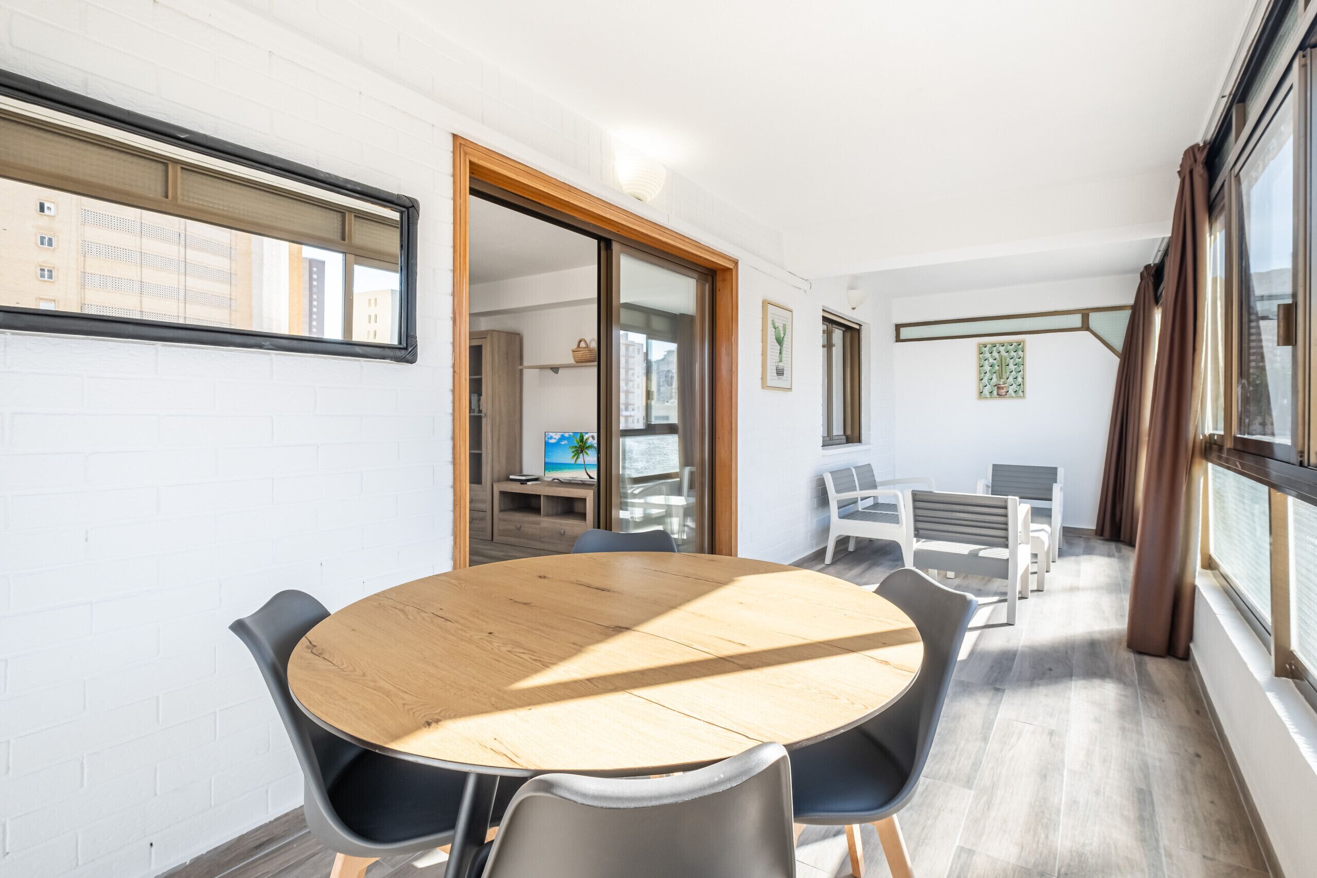 Una sala de reuniones moderna con una mesa redonda de madera, sillas negras y un ventanal con vistas a edificios.