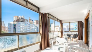 A balcony with a view of a cityscape, white furniture, and a table with chairs. - Waldorff 4-A (Benidorm)