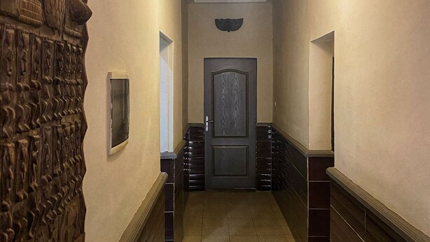 A hallway with a wooden wall carving, a door, and a light fixture.