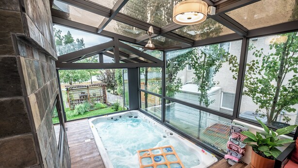 Un bain à remous avec une terrasse en bois, de grandes fenêtres et un ventilateur de plafond.