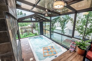 Un jacuzzi con terraza de madera, ventanas amplias y un ventilador de techo.