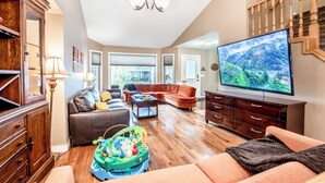 Un salon spacieux doté d’un grand téléviseur à écran plat, d’un meuble en bois, d’un canapé et d’une table basse.