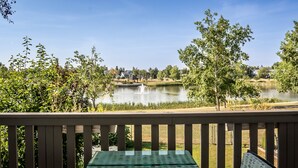 Une vue depuis un balcon donnant sur un lac avec une fontaine, entouré d’arbres et sous un ciel dégagé.