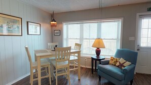 A dining area with a table and chairs, a lamp, and a window with blinds. - Walk to Sandfest, Shared Pool, Boardwalk to the Beach (Port Aransas)