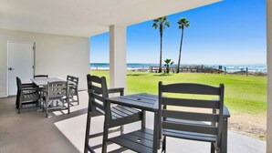A covered outdoor seating area with a view of the beach and ocean. - Summer House 106B | Ground floor, wrap around deck, direct beach front! (Orange Beach)