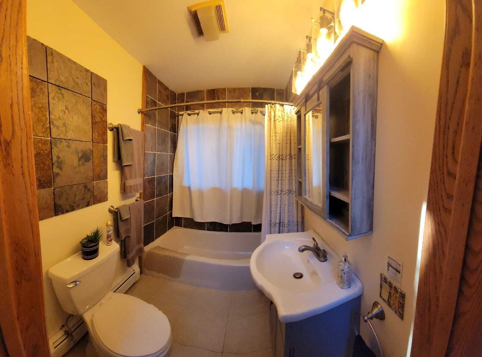 A bathroom with a toilet, sink, bathtub, and shower.