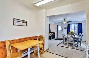 Un espace repas comprenant une table et des chaises en bois, un banc, un ventilateur de plafond et un tapis.