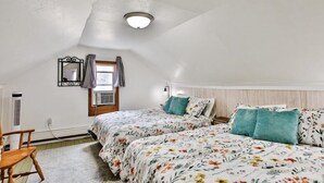 Ein Schlafzimmer mit zwei Betten, einem Deckenventilator, einem Fenster mit Vorhängen und einem Wandheizkörper.