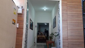 A hallway with a wooden wall, a white door, and a dining area in the background. - Lar Recife Olinda - Casa Inteira (Recife)