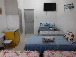 A small, simple room with two beds, a desk, a chair, and a TV. - Lar Recife Olinda - Casa Inteira (Recife)
