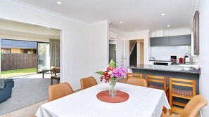 A modern kitchen with a large island, a dining area with a table and chairs, and a view of a backyard.