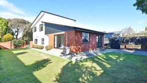 A modern two-story house with a brick facade, large windows, and a well-maintained lawn.
