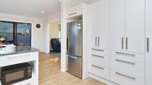 A modern kitchen with white cabinetry, a stainless steel refrigerator, and a built-in microwave.