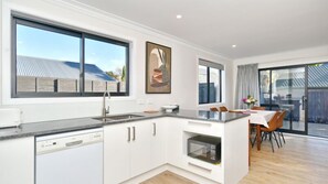 A modern kitchen with white cabinetry, a dishwasher, and a large window.