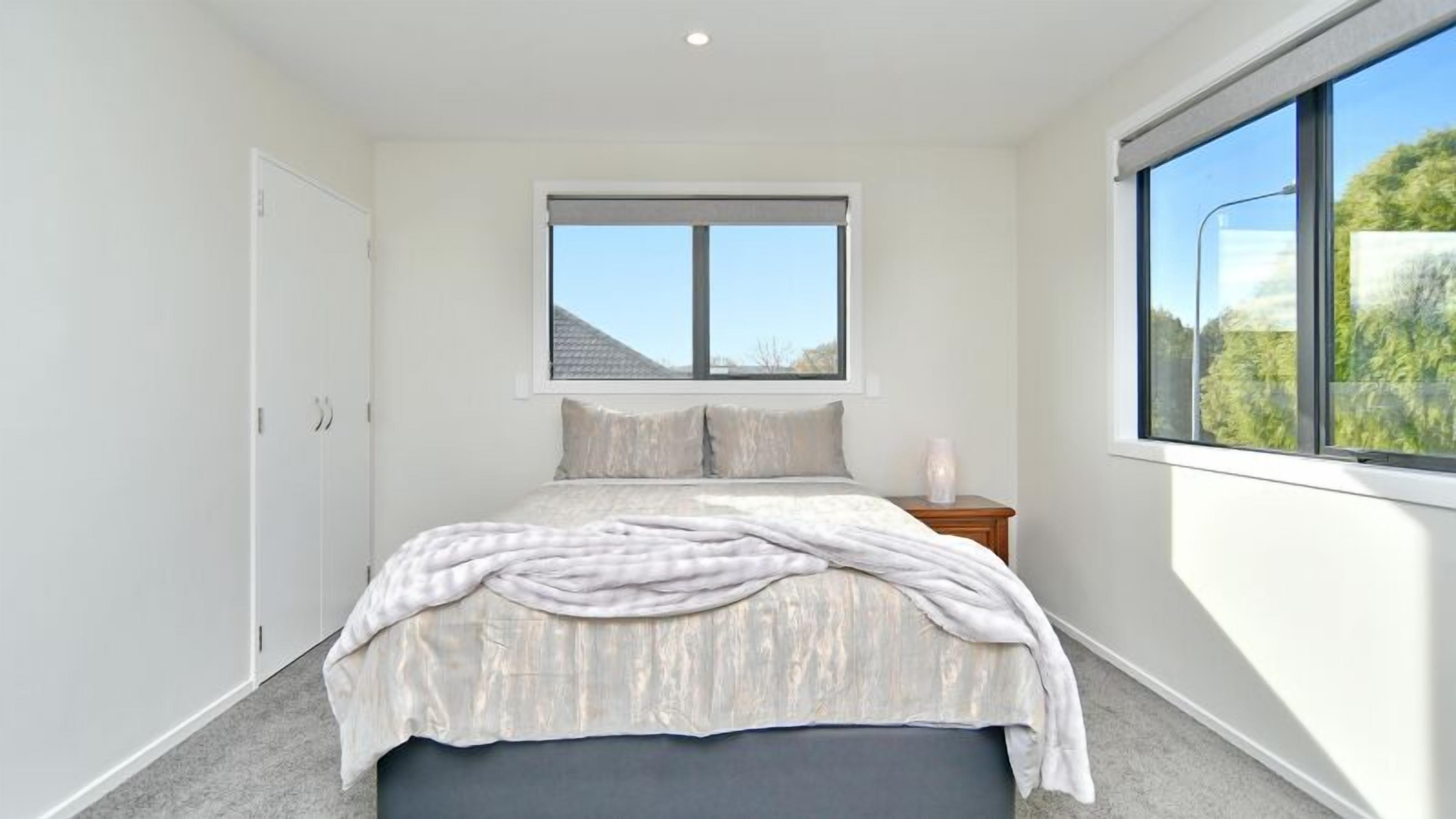 Un dormitorio con cama, ventana y mesita de noche.