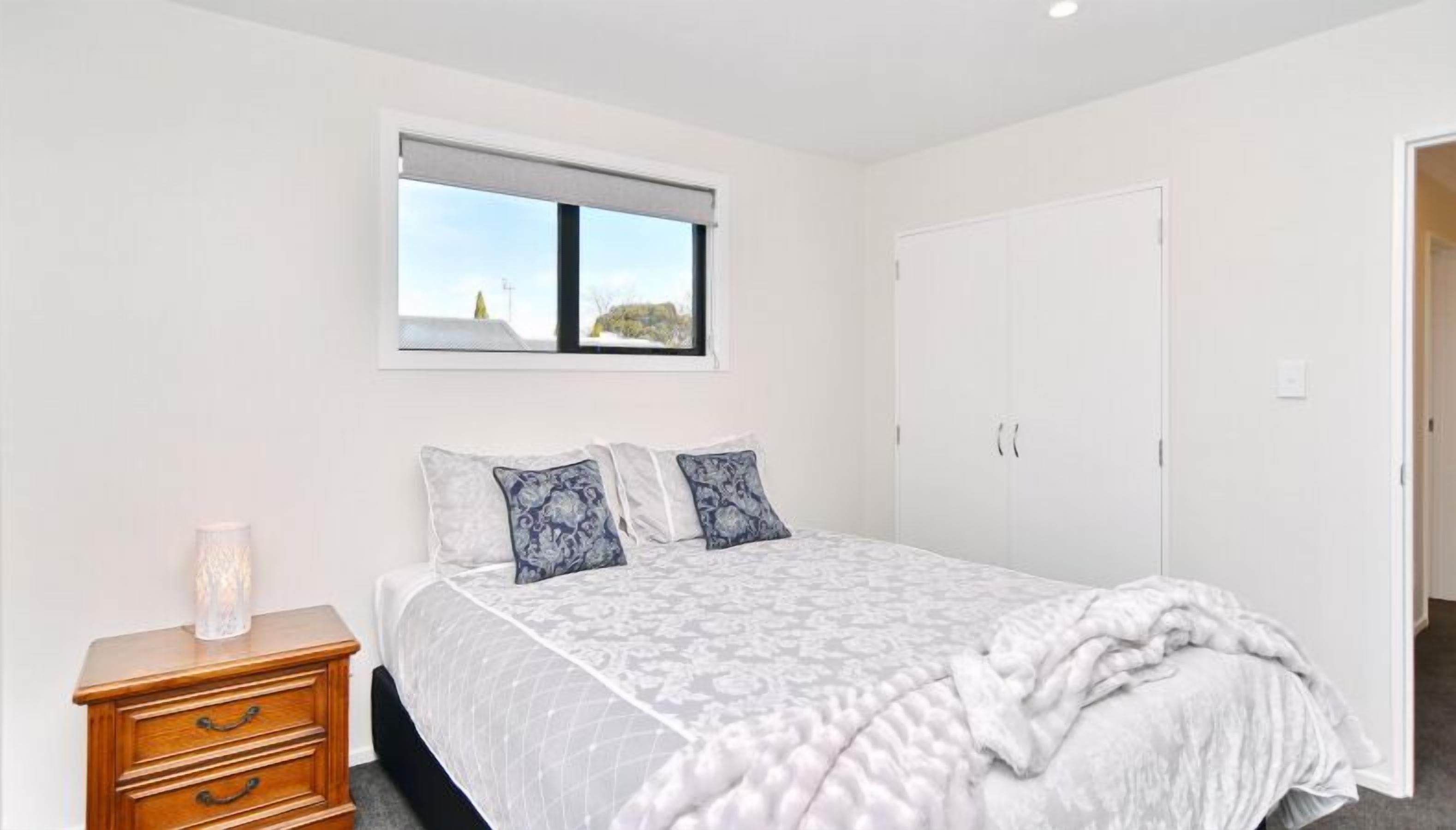 Un dormitorio con cama, mesita de noche, ventana con vistas y armario.