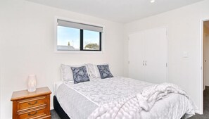 Un dormitorio con cama, mesita de noche, ventana con vistas y armario.