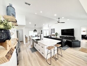 A modern kitchen with a large island, bar stools, and a built-in oven.