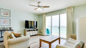 Un salon avec un canapé, une table basse, un téléviseur et un balcon offrant une vue agréable.