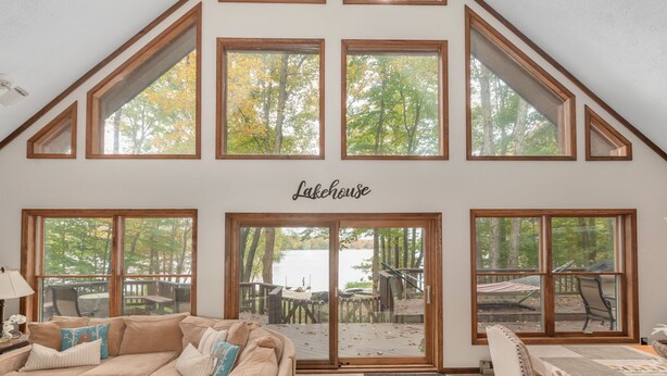 Una habitación con techo inclinado, ventanas amplias, un sofá y un letrero que dice 'Lakehouse'.