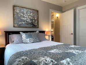 Cozy retreat with a large bed, framed artwork, and a nightstand with a lamp.