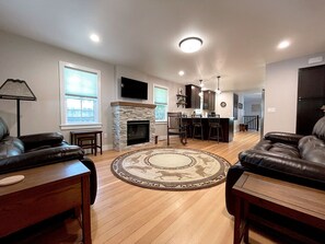 A spacious living room with a fireplace, leather sofas, a coffee table, and a large rug.