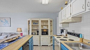 A compact kitchen with a stove, microwave, and cabinets.