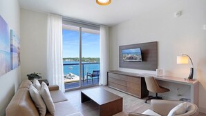 Ein modernes Wohnzimmer mit großem Fernseher, einer Couch, einem Couchtisch und Blick aufs Meer.