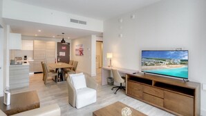 A modern living room with a TV, a dining area, and a kitchen. - Luxury Ocean Breeze Condo W/ Balcony at CH-CS22 (Hollywood)