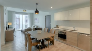 A modern kitchen with a dining area, featuring light wood cabinetry, a stainless steel sink, and a central island with seating. - Luxury Ocean Breeze Condo W/ Balcony at CH-CS22 (Hollywood)