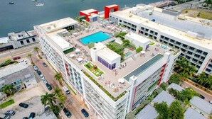 Ett modernt hotell med en pool på taket, flera balkonger och utsikt över vattnet.