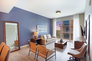 Een moderne woonkamer met een bank, stoelen, een salontafel, een lamp en een groot raam met uitzicht.