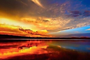 Ein Sonnenuntergang über einem stillen See, im Wasser spiegeln sich die Farben des Himmels.