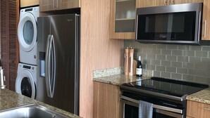 Una cocina moderna con encimeras de granito, electrodomésticos de acero inoxidable, armarios de madera y microondas integrado.