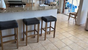 Una cocina con encimera de granito, taburetes de madera, microondas y ventilador de techo.