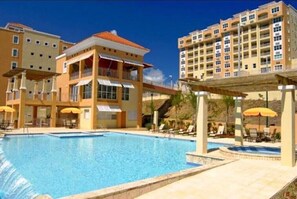 A hotel with a swimming pool, outdoor seating, and multiple balconies. - Nest by the Marina (Fajardo)