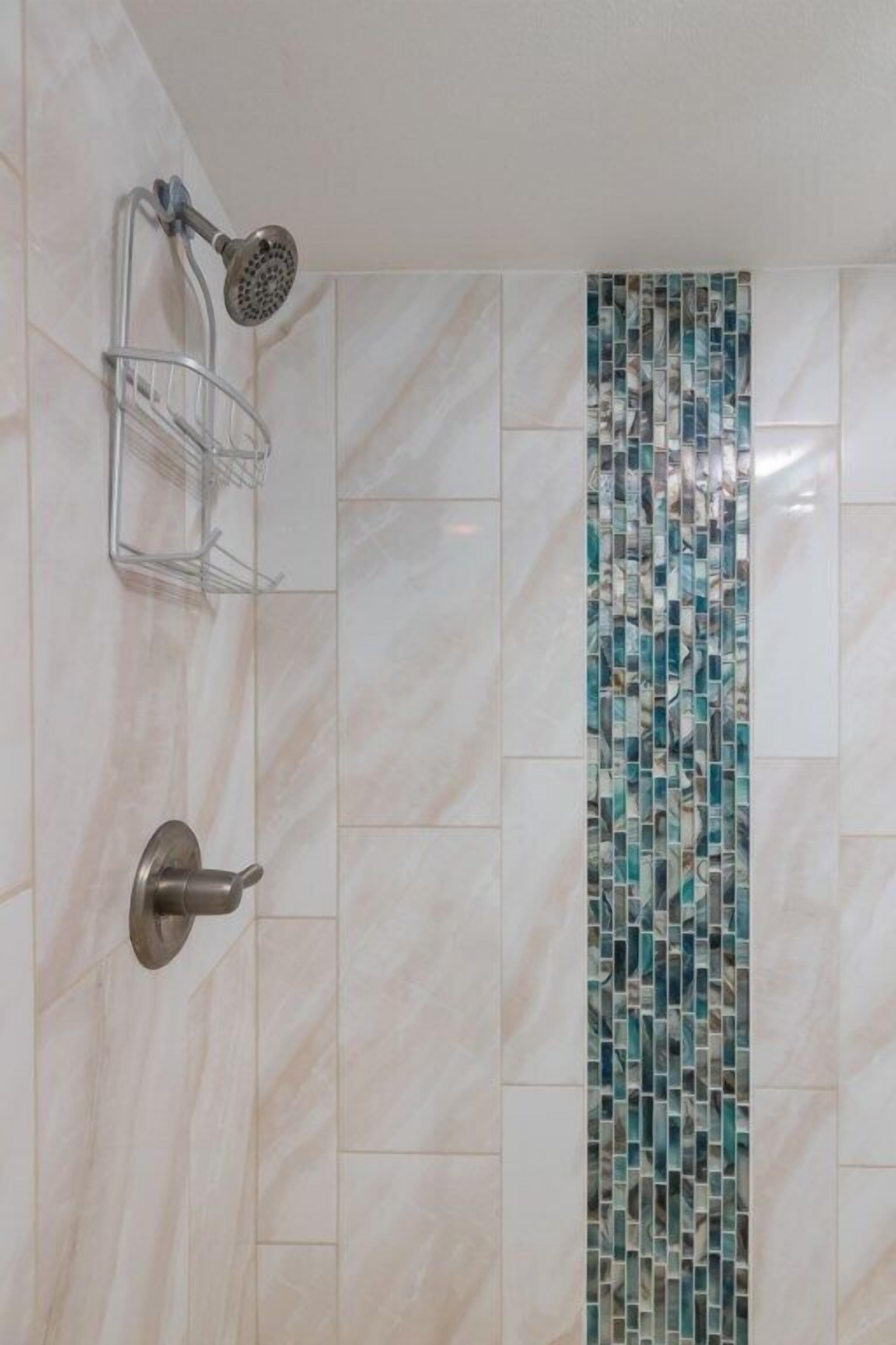 Un baño con ducha, un perchero metálico y un revestimiento de azulejos decorativos.