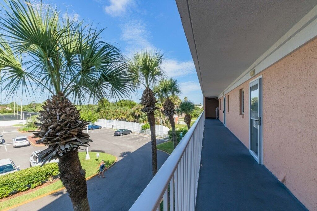 A balcony with a view of a parking lot and palm trees.