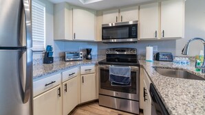Eine moderne Küche mit Edelstahlgeräten, weißen Schränken und Granit Arbeitsplatten sowie einem eingebauten Backofen.
