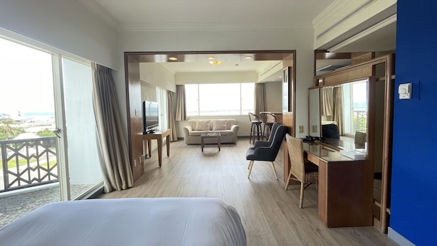 A hotel room with a large bed, a desk with a chair, a sofa, and a television. There is a balcony with a view of the city. - Dongxu Resort Hotel (Hualien City)