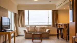 A living room with a sofa, a coffee table, a TV, and a dining area with chairs. - Dongxu Resort Hotel (Hualien City)