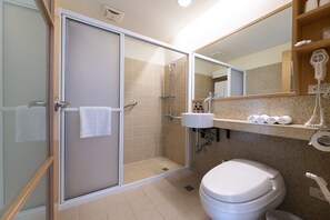 Un baño moderno con ducha envuelta en vidrio, inodoro blanco y tocador con espejo y perchero.
