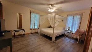 Un dormitorio con cama con dosel, ventilador de techo y escritorio con silla.