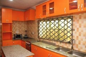 A kitchen with orange cabinets, a window with a checkered pattern, and a sink. - Impeccable , modern House in Benin City, Nigeria (Benin City)