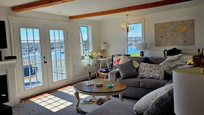 A living room with a sofa, coffee table, and a map on the wall. - Spectacular Corea Harbor side Home minutes to Acadia National Park Schoodic Gate (Gouldsboro)