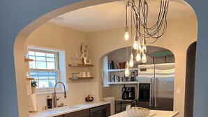 Een moderne keuken met een centraal eiland, inbouwapparatuur en hangende lampen.