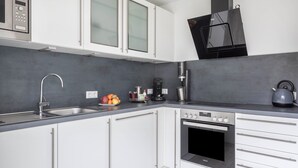 A modern kitchen with white cabinets, a built-in oven, a coffee maker, and a kettle on the counter. - Pet-Friendly Apartment Holly with Wi-Fi & Terrace (Ebringen)